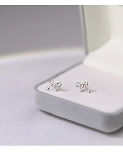 Macro shot of S999 sterling silver bow knot stud earrings on a velvet jewelry box