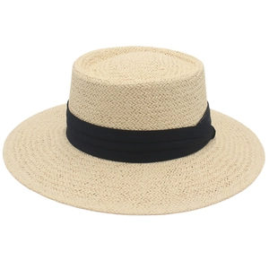 Detail of a beige woven boater hat with a flat top and elegant black ribbon band