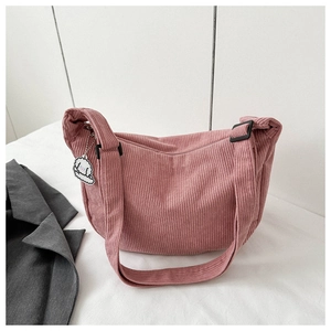 Pink corduroy crossbody bag featuring a cute white dog charm on a white background