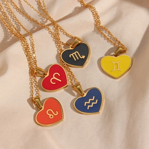 Close-up of golden necklaces with heart-shaped enamel pendants featuring zodiac signs