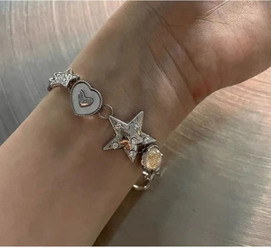 Detail of silver link bracelet featuring star and heart charms with inlaid rhinestones
