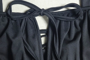 Détail du décolleté d'une robe noire avec un nœud à cordon et des détails de laçage croisé