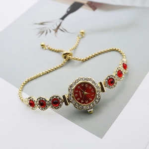 Detail of gold quartz bracelet watch with red stones and adjustable sliding chain