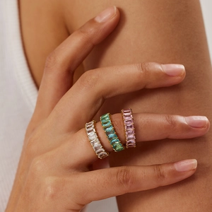 Trois bagues éternité dorées avec zircons rectangulaires colorés portées par un mannequin