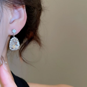 Close-up of sparkling waterdrop teardrop earrings with crystals worn by a model