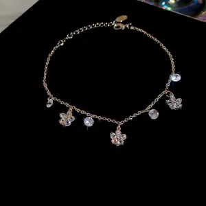 Bracelet de cheville doré avec fleurs en zircon et cristaux ronds sur fond noir chic