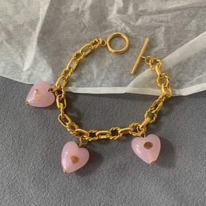 Detailed shot of pink Murano glass heart charms on a gold-plated link bracelet with OT clasp