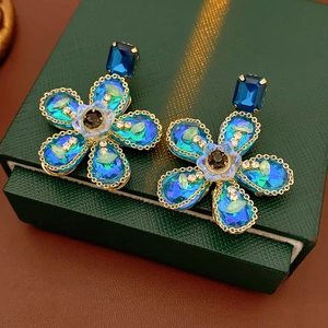 Gros plan détaillé des boucles d'oreilles fleurs bleues avec base dorée et cristaux