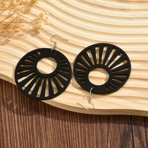 Chic black round hollow wooden earrings with geometric pattern on wooden tray