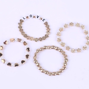Détail de quatre bracelets en perles dorées avec perles nacrées, cœurs, étoiles et LOVE