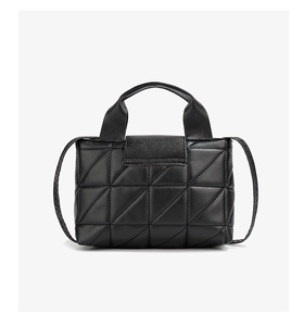 Close-up of black quilted faux leather handbag with geometric patterns and top handle