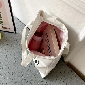 Detail view of large white canvas tote bag with pink lining and interior book storage