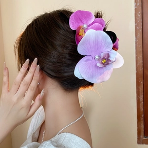 Detail view of pink orchid hair claw clip with pearls worn on elegant hairstyle