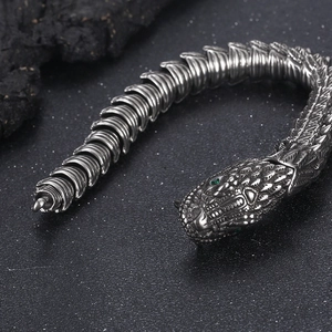 Detail of vintage silver dragon head bracelet with green gemstone eyes in punk style