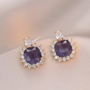Detailed view of vintage flower heart earring with purple zircon on silk background