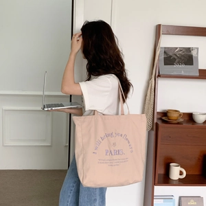 Detail of soft pink canvas tote bag featuring embroidered lettering and large capacity