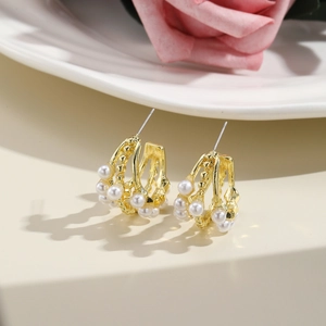 Detail view of vintage triple-layer gold earrings with elegant white pearls on a vanity
