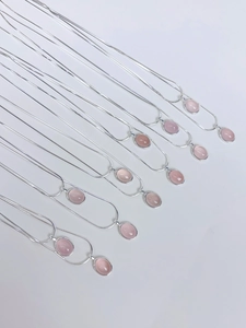 Detail von sieben S925 Sterlingsilber-Halsketten mit rosa Chalzedon-Anhängern auf Weiß