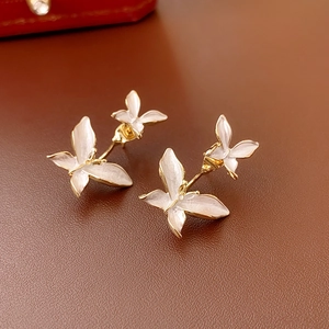 Macro de boucles d'oreilles papillon dorées avec émail blanc sur cuir marron