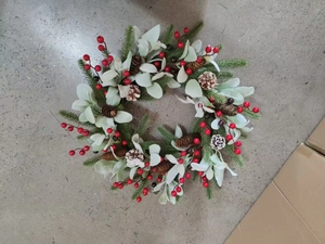 Close-up of Christmas wreath featuring pine needles, red berries, and natural pine cones