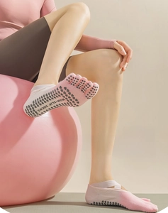 Detail of pink five-toe yoga socks with non-slip grip dots and cross strap design