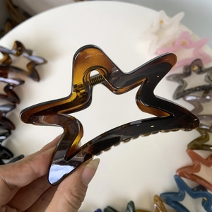 Detailed view of amber star-shaped hair claw clip with cutout design and high-elastic spring
