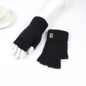 Detailed view of black knitted fingerless gloves with leather deer patch on white background