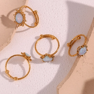 Detail of 18K gold plated adjustable rings with opal center stones on water drops surface