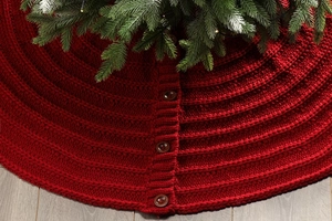 Close-up of red knitted Christmas tree skirt with wooden button and soft yarn texture