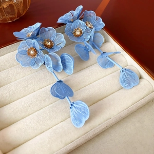 Macro de boucles d'oreilles fleurs en maille bleu clair avec détails de strass dorés