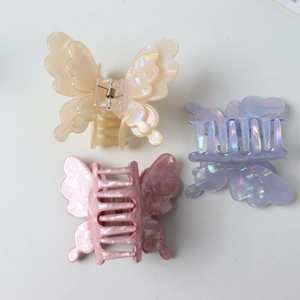 Three elegant acetate butterfly hair claws in iridescent pink, cream, and purple colors