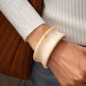 Gros plan d'un large bracelet en résine à texture marbrée porté par un mannequin