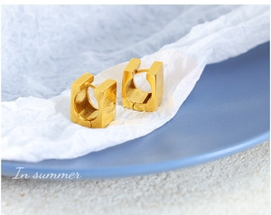 Macro shot of 18K gold plated U-shaped earrings with mirror finish and secure closure