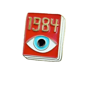 Detailed view of 1984 book enamel pin with blue evil eye design and golden metal edges