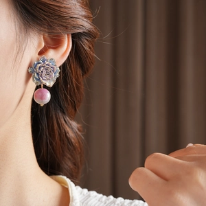 Détail d'une boucle d'oreille rose bleue avec perle rose portée avec lumière douce