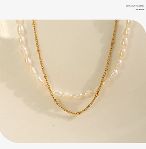 Close-up of double-layered gold chain necklace with white freshwater pearls on a bust