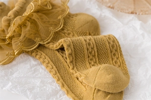 Close-up of yellow knit cotton children's socks featuring delicate lace trim and cable pattern