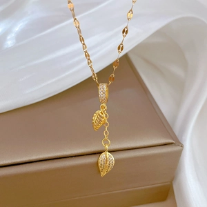 Detail of golden tassel leaf pendant necklace with zircon inlays on a jewelry box