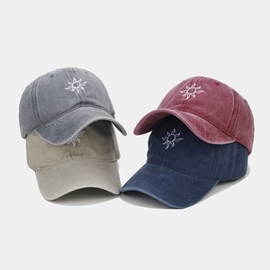 Detail of four washed cotton baseball caps with sun embroidery in multiple colors