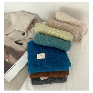 Detailed close-up of colorful wool blend knitted scarves with minimalist egg fabric label
