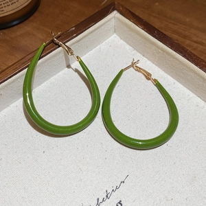 Detailed view of green enamel drop earrings displayed on a minimalist wooden jewelry tray