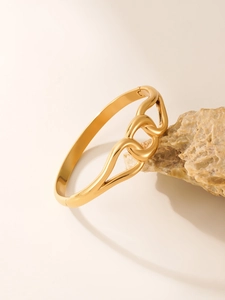 Detail view of interlocking golden wave bangle on a textured natural stone base