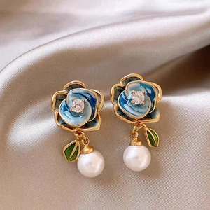 Détail de boucles d'oreilles fleur bleue, émail doré, cristaux et perles sur soie