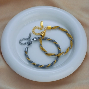 Two-tone woven titanium steel twisted bracelet with lobster clasp on silk background