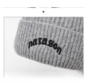 Detail display of gray ribbed knit beanie with black paragon embroidery text