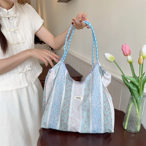 Detail of floral and striped canvas tote bag with woven blue handles and brand label