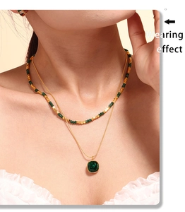 Dettaglio collana doppia dorata con pendente in pietra verde su collo di modella