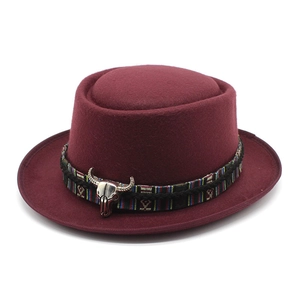 Close-up of wine red wool pork pie hat with ethnic woven band and silver bull skull charm