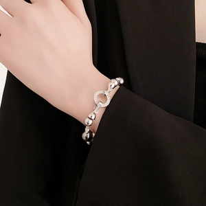 Close-up of a silver clasp bracelet with grey pearls and pavé zircons on a model's wrist
