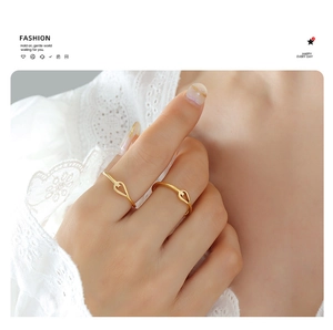 Detail shot of two gold hollow heart rings worn by a model against white lace
